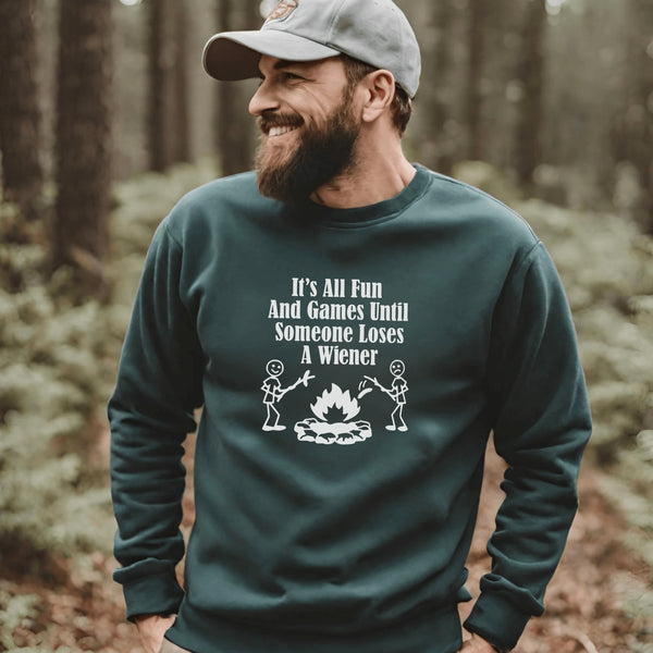 Our Camping sweatshirt features two stick people roasting wieners over a campfire with the hilarious saying, "It's All Fun & Games Until Someone Loses A Wiener."
